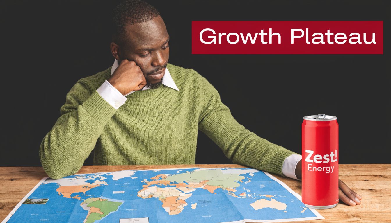 A man in a green sweater looks at a world map while holding a Zest Energy drink can.