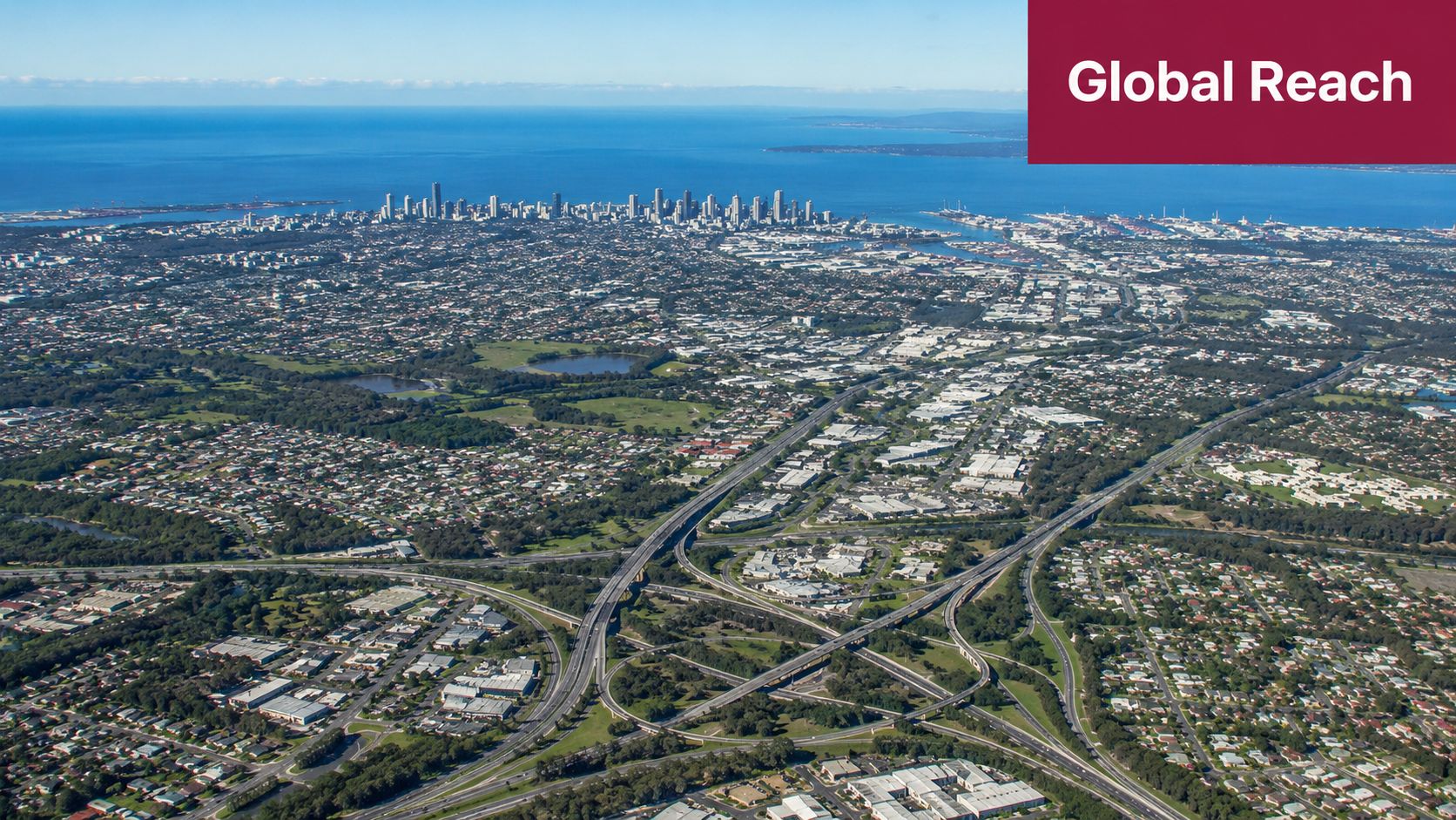Aerial view of the Gold Coast city skyline, coastline, and surrounding urban infrastructure with highways.